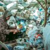 A woman sits under a tree surrounded by dry waste in East Java.