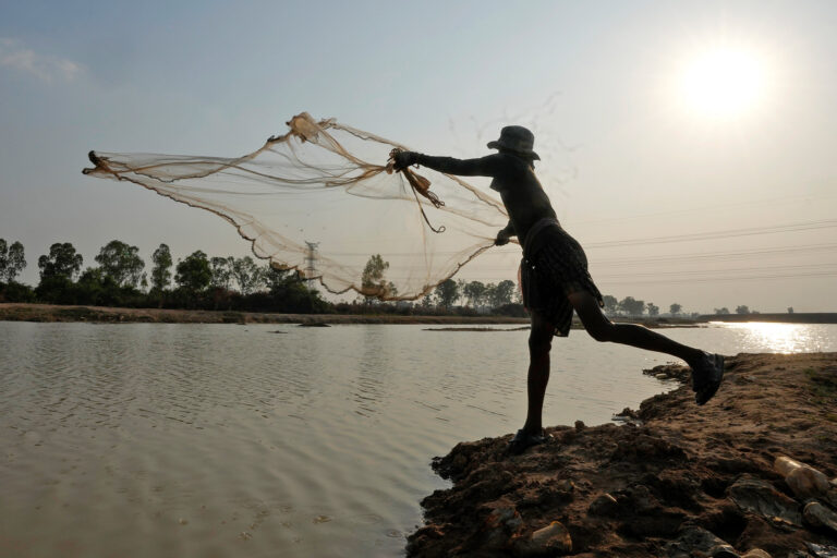 A fisher casts a small fishing net to catch fish for his family outside Phnom Penh, 2024.