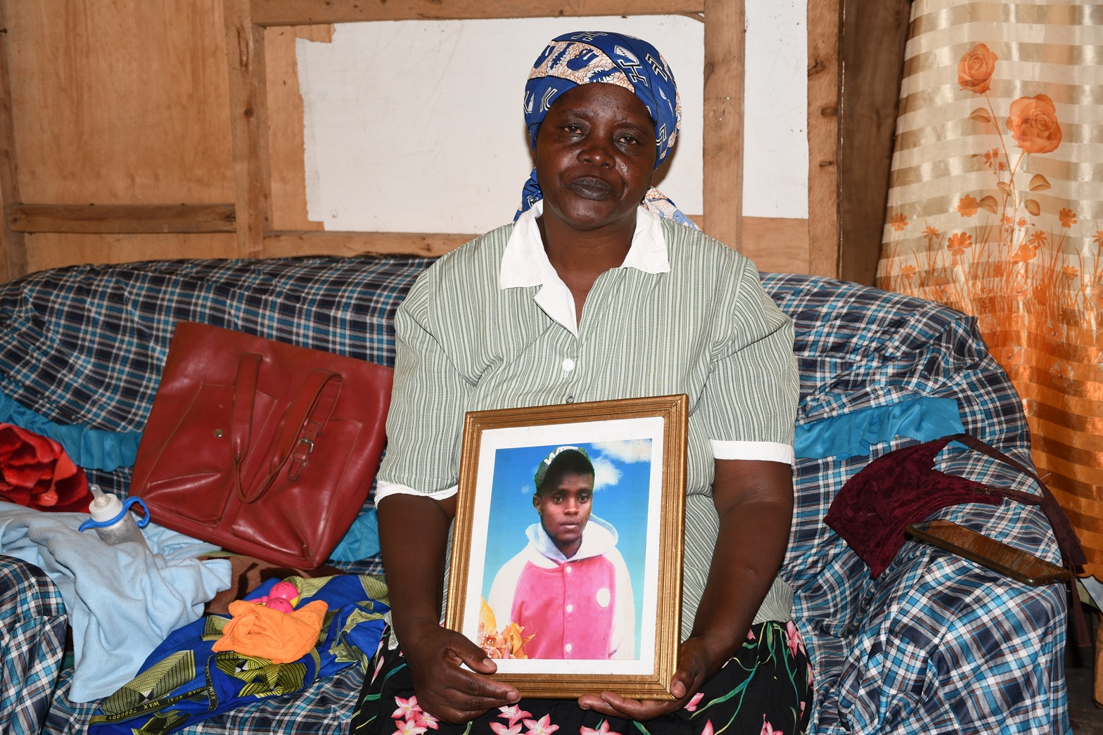 Grace Nyambura Kamau holds a photo of her son, Samuel Mwangi Kimani, at her home in Karagita, Naivasha, Kenya. Image courtesy of Willy Dennis Njiru.