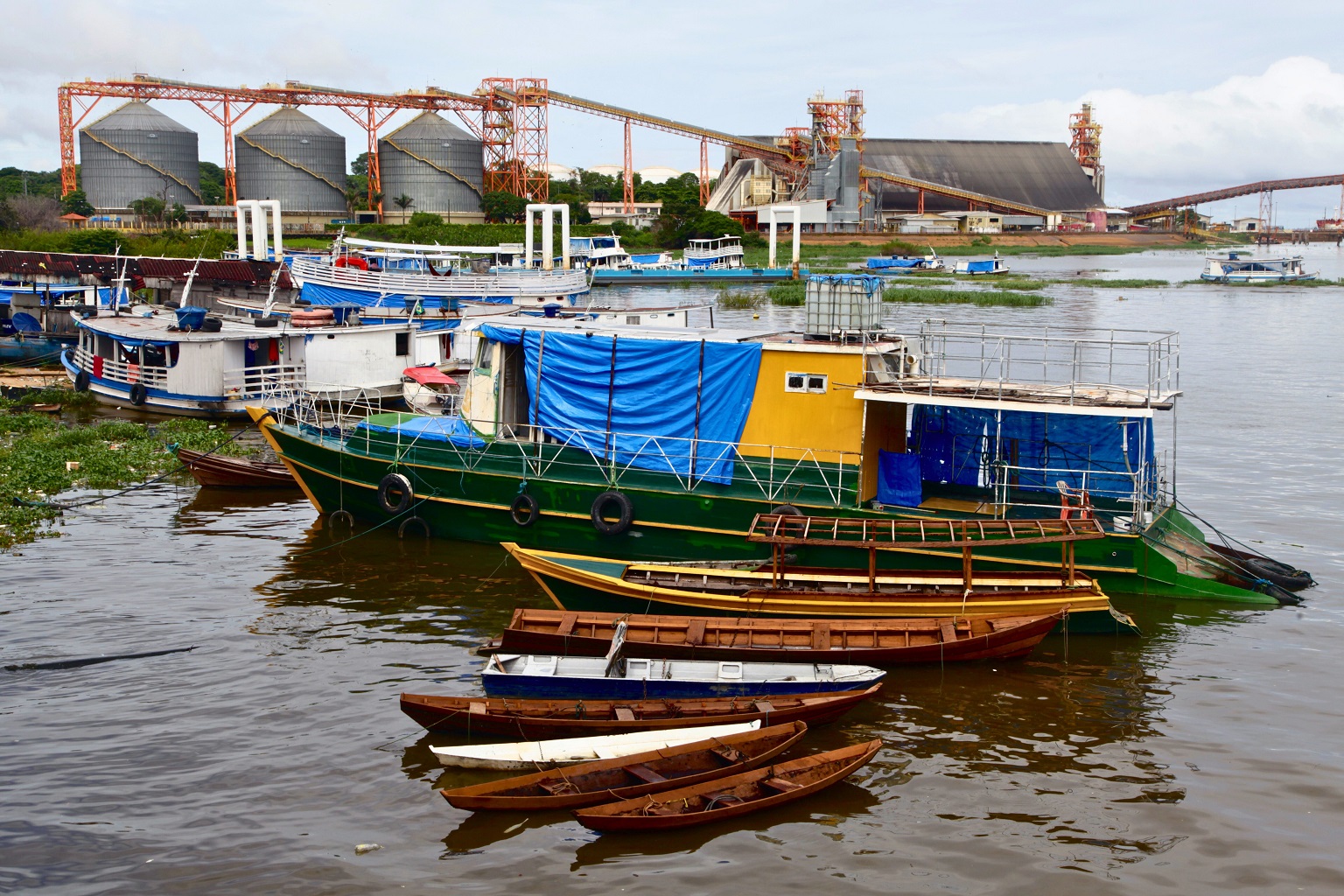 Small boats floating on the Tapajós River against the backdrop of the giant Cargill soy terminal.