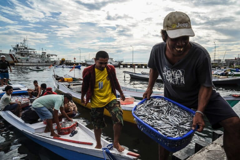 Small-scale fishers unloading buckets of fish from their boats in South Sulawesi, Indonesia.