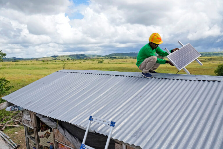 A worker of a sustainable solutions company performs maintenance work on a solar panel on a roof on the island of Sumba in Indonesia.