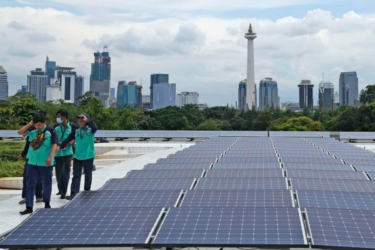 Workers walk near solar panels that provide partial electrical power to a major mosque in Jakarta.