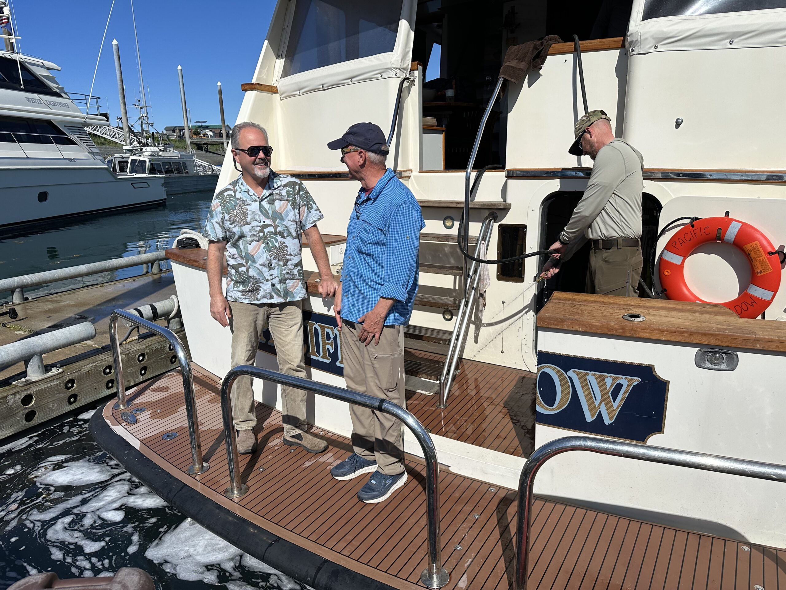 Roarke Brown, left, joins two deckhands in the busy Homer harbor aboard his charter boat the Pacific Shadow.
