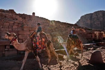 A Jordanian Bedouin boy leads a tourist on a camel through the ancient city of Petra, Jordan. World Cultural Heritage sites made out of stone are at risk from the effects of severe weather and climate change.
