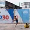 A boy kicks a soccer ball near signage for the COP30 U.N. Climate Conference in Belem, Brazil, March 23, 2025. Image by AP Photo/Jorge Saenz.
