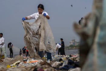 Volunteers clean up plastic and other waste materials on a beach on the Arabian Sea coast on World Environment Day in Mumbai. Environmental crises are lived experiences for young generations today — including journalists. Image by AP Photo/Rafiq Maqbool, File.