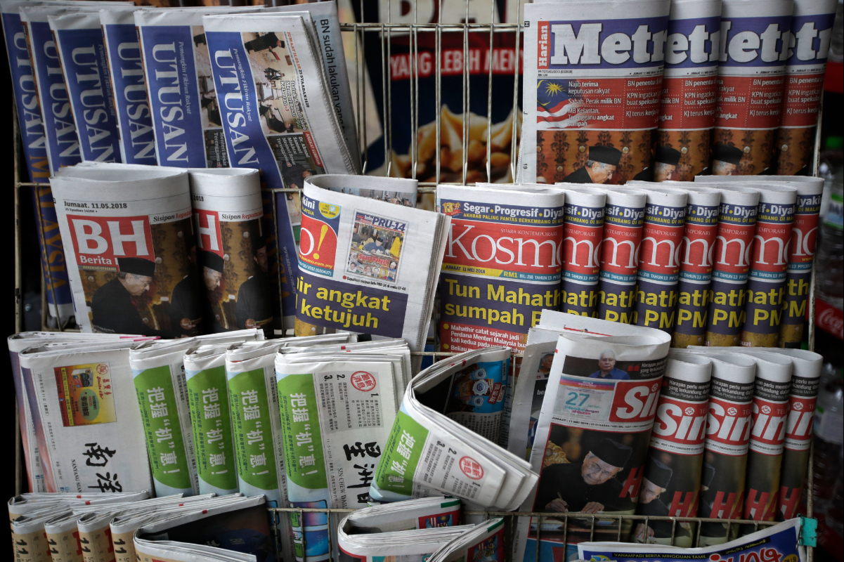 Newspapers with headlines of Mahathir Mohamad's swearing-in as Malaysia's new prime minister are displayed for sale at a convenience shop in Kuala Lumpur in 2018. Today, the media landscape is shifting with AI, social media and changes in readership. Image by AP Photo/Andy Wong.