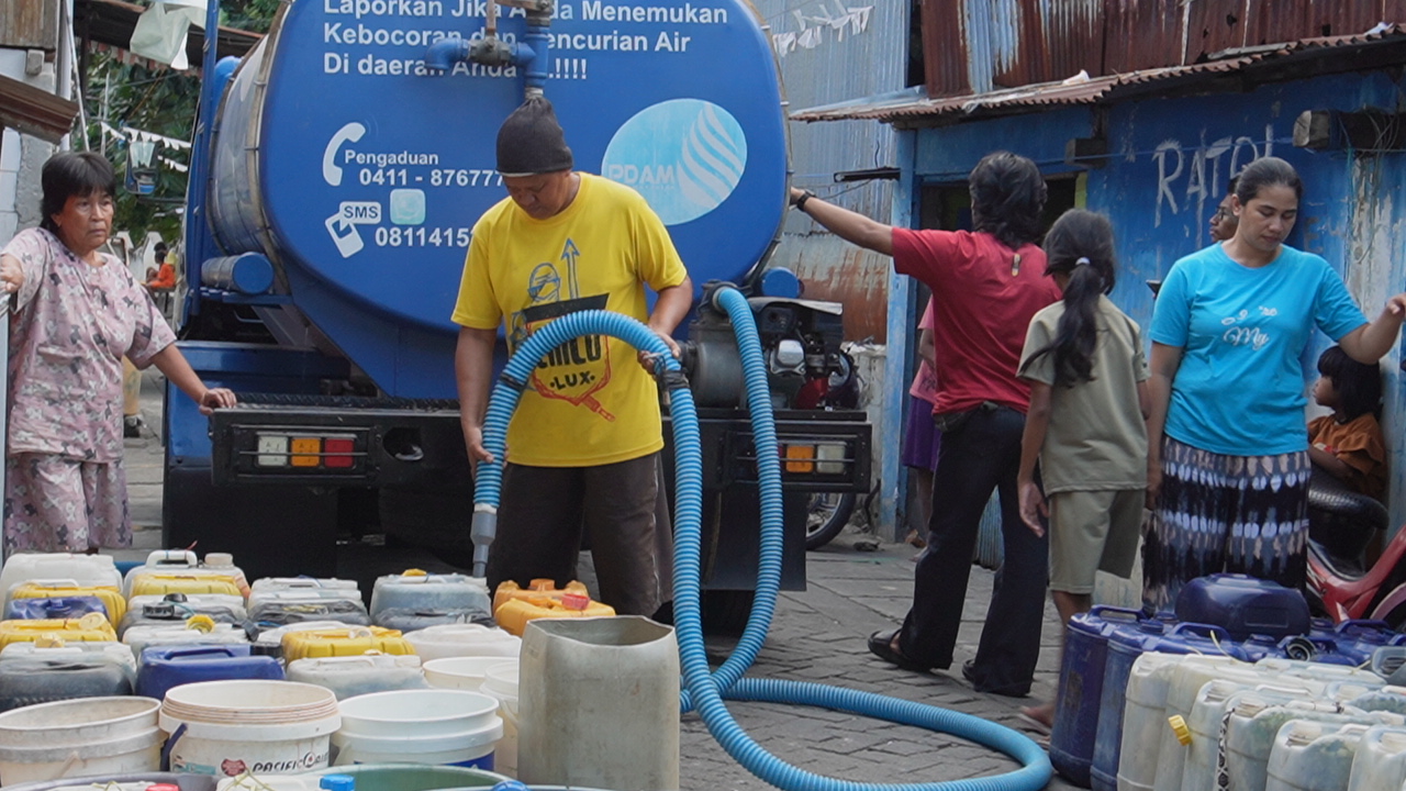 Residents queue for clean water aid from a PDAM water tanker.