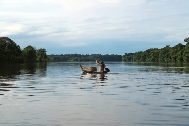 A woman from the Indigenous Macaquiño community in Vaupés pushes her boat across the Vaupés River towards her traditional forest garden, or chagra. Image by Aimee Gabay/Mongabay.