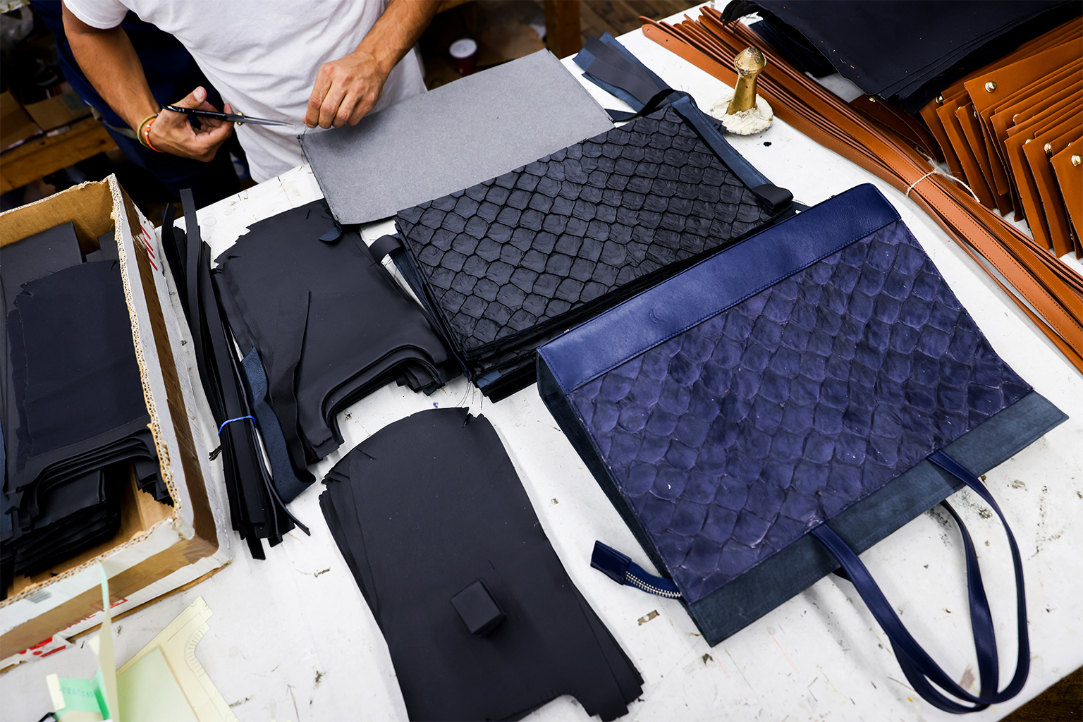 Alex Dabagh observa um protótipo enquanto monta bolsas de couro pirarucu, em novembro de 2022, em Nova York.