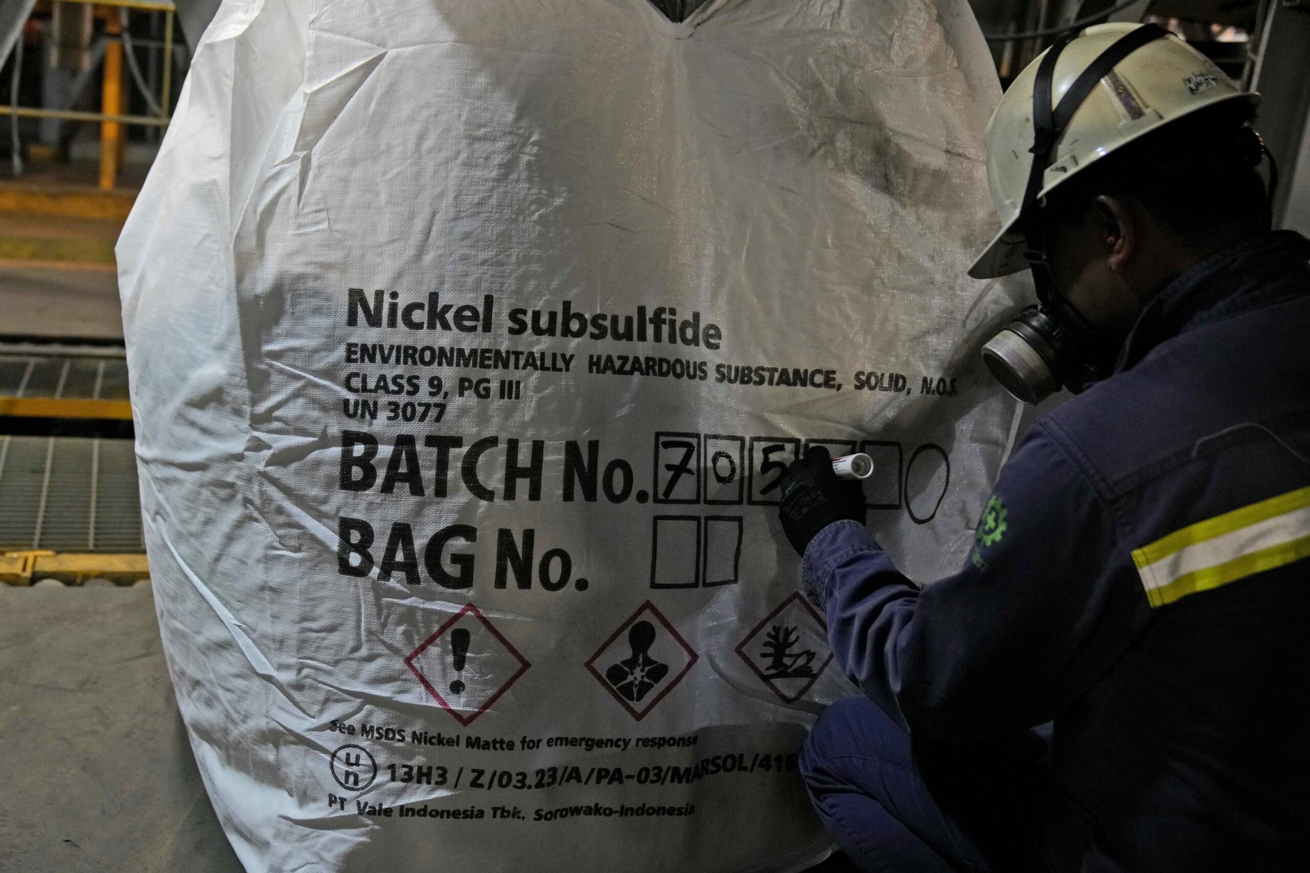 A worker writes batch numbers on a bag of nickel matte at PT Vale Indonesia's processing plant in Sorowako, South Sulawesi, Indonesia, Tuesday, Sept. 12, 2023. Demand for critical minerals like nickel and cobalt is surging as climate change hastens a transition to renewable energy, boosting carbon emissions by miners and processors of such materials. Image by AP Photo/Dita Alangkara.