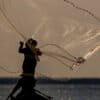 A fisherman is silhouetted as he casts his net into the Tapajos River in Santarem, Para state, 2020.