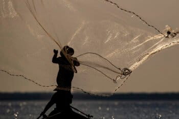 A fisherman is silhouetted as he casts his net into the Tapajos River in Santarem, Para state, 2020.