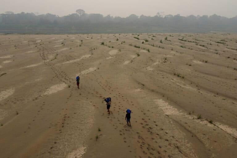 Residents transport drinking water along the dry Madeira River, a tributary of the Amazon River, during the dry season, in 2024. Image by AP Photo/Edmar Barros.