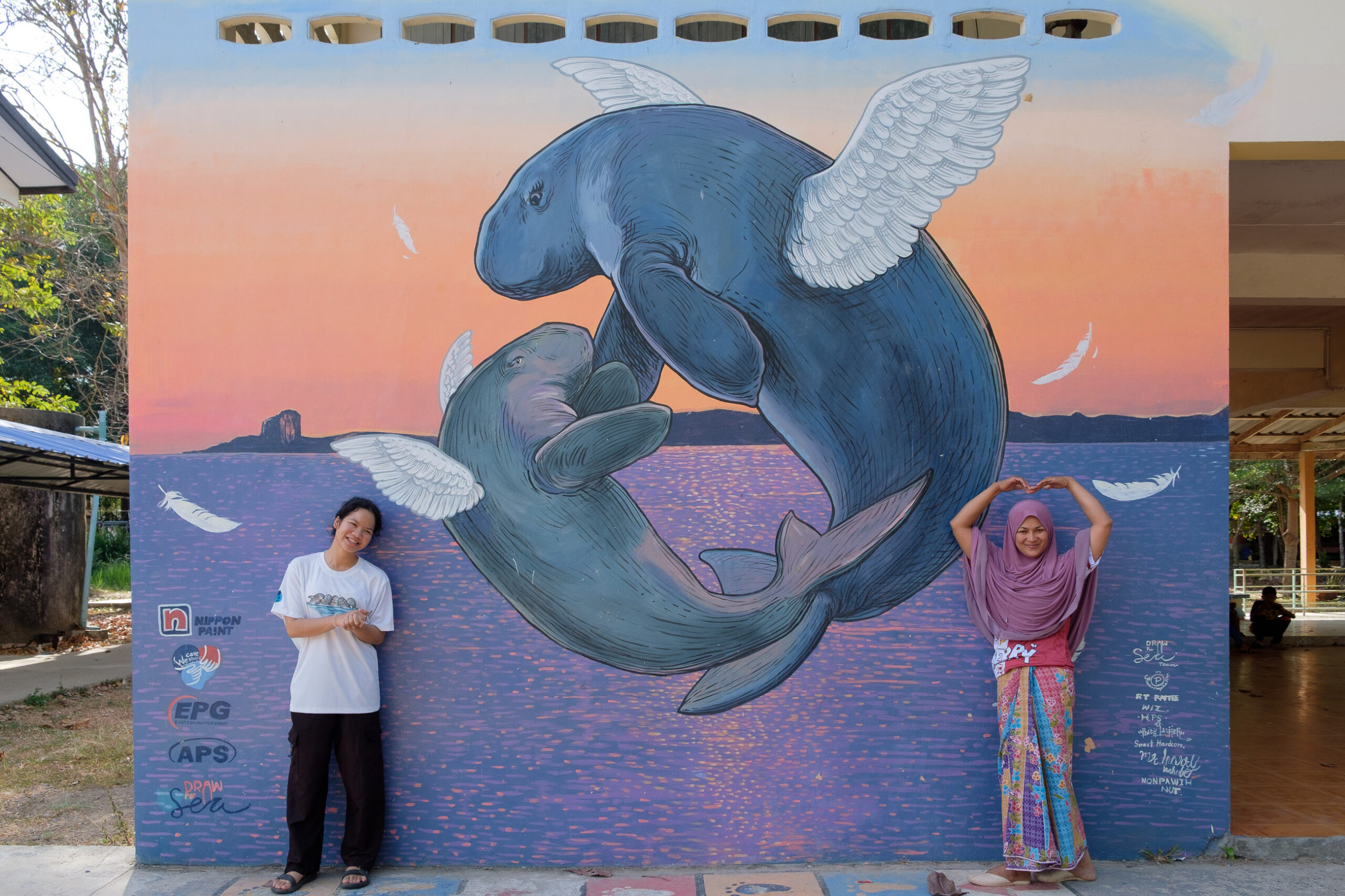 Volunteers next to dugong mural in Thailand