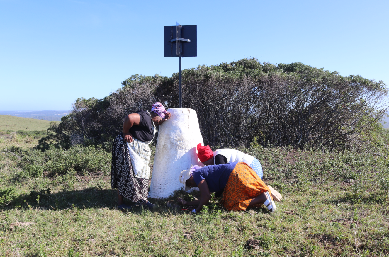 Boneka Mema, Thandazwa Sizani and Primrose Ndongeni pray to stop the mine at the village’s sacred beacon. Image by Anna Weekes for Mongabay.