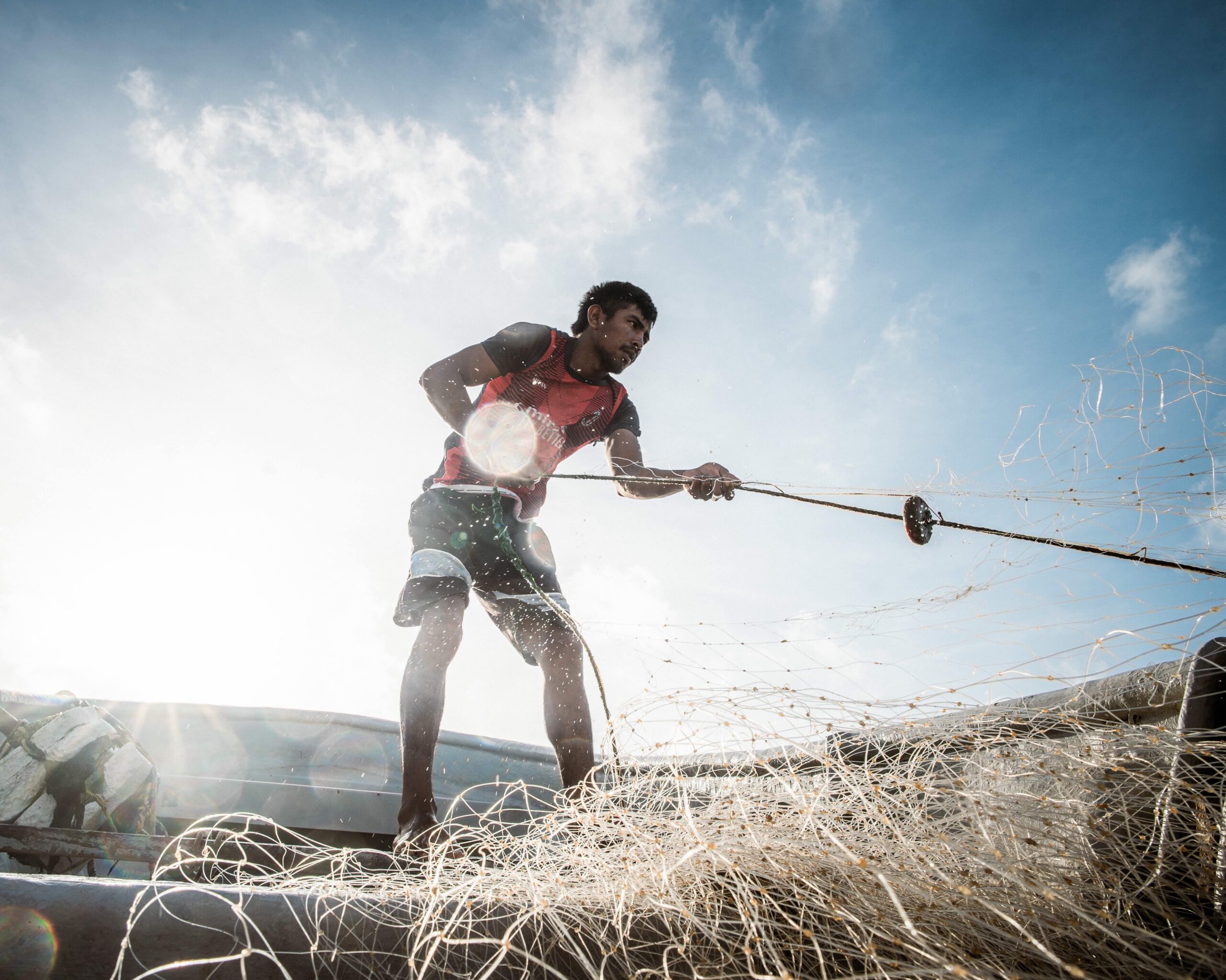 Wilfrido Arends’ 22-year-old son, known as “Caraquitas” (“Little Caracas”) after his father, hauls a fishing net into the boat. Image by Euan Wallace.