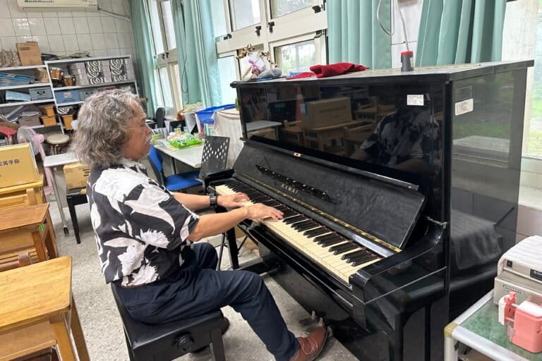 Philippine-born Siraya activist and musician Edgar Macapili plays a piano in a classroom at Koupi Experimental Elementary School in Sinhua district, Tainan, Aug. 21, 2026. Image by Aylin Ho for Mongabay.