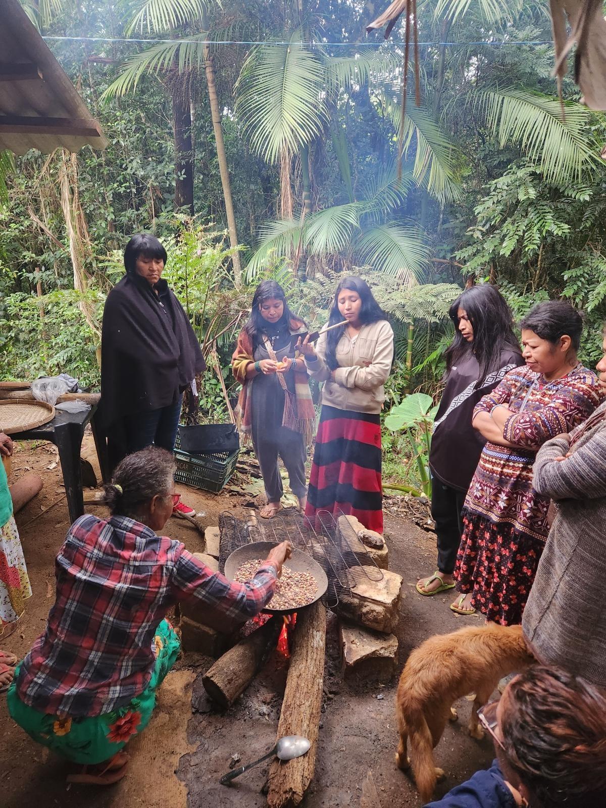 On the right, with arms crossed, Kerexu Cleonice, leader and sister of Karaí Tiago, observes the preparation of traditional Guarani food in an exchange with Ehuana Yanomami (standing, on the left). Photo by Ana Maria Machado via ISA.