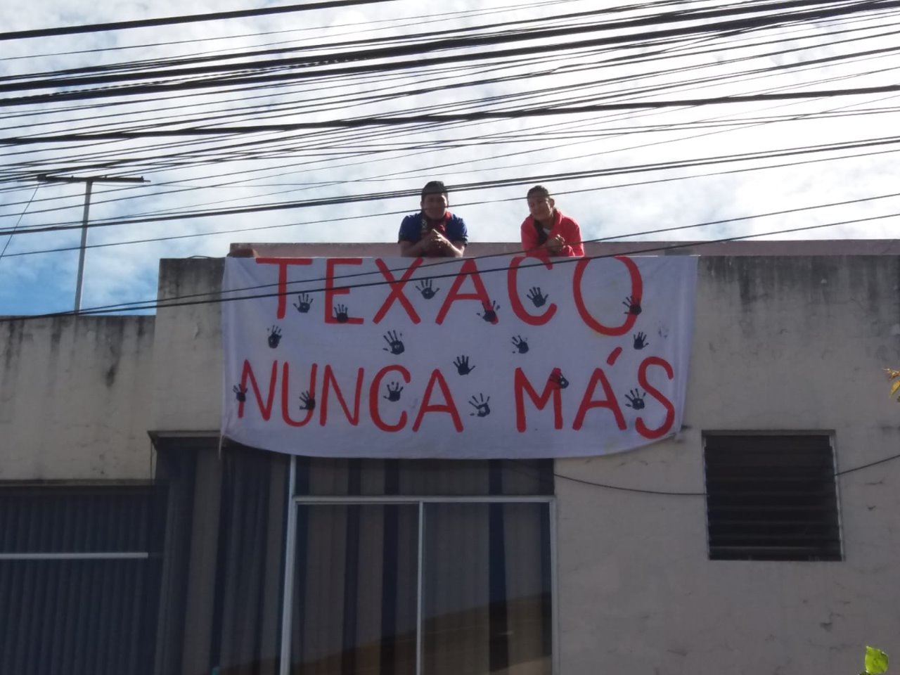 En el edificio donde funcionan las oficinas de la Udapt colgaron un cartel para recordar los daños causados por la petrolera. Foto: Unión de Afectados por la Petrolera Chevron (Udapt).