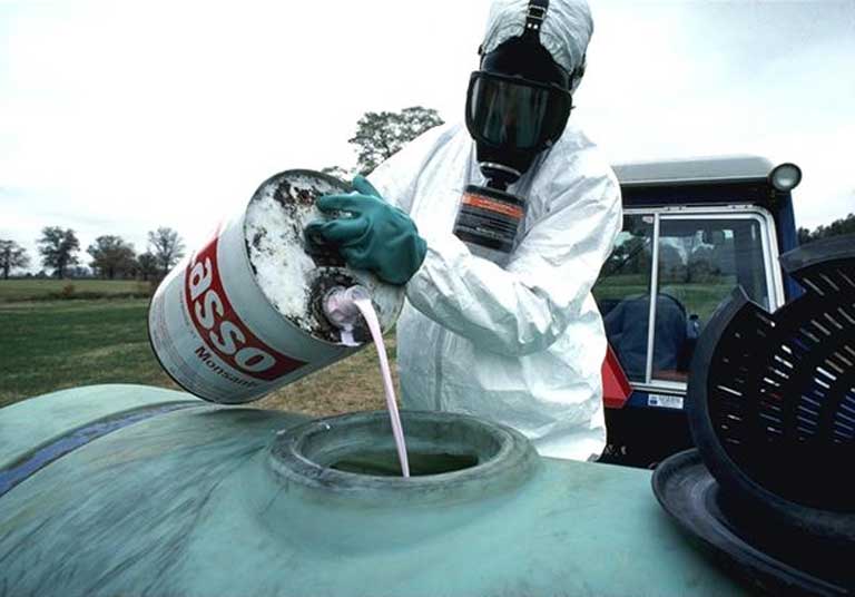 El herbicida Monsanto Lasso que será rociado en los cultivos de alimentos con el equipo de protección adecuado. Foto cortesía de USDA