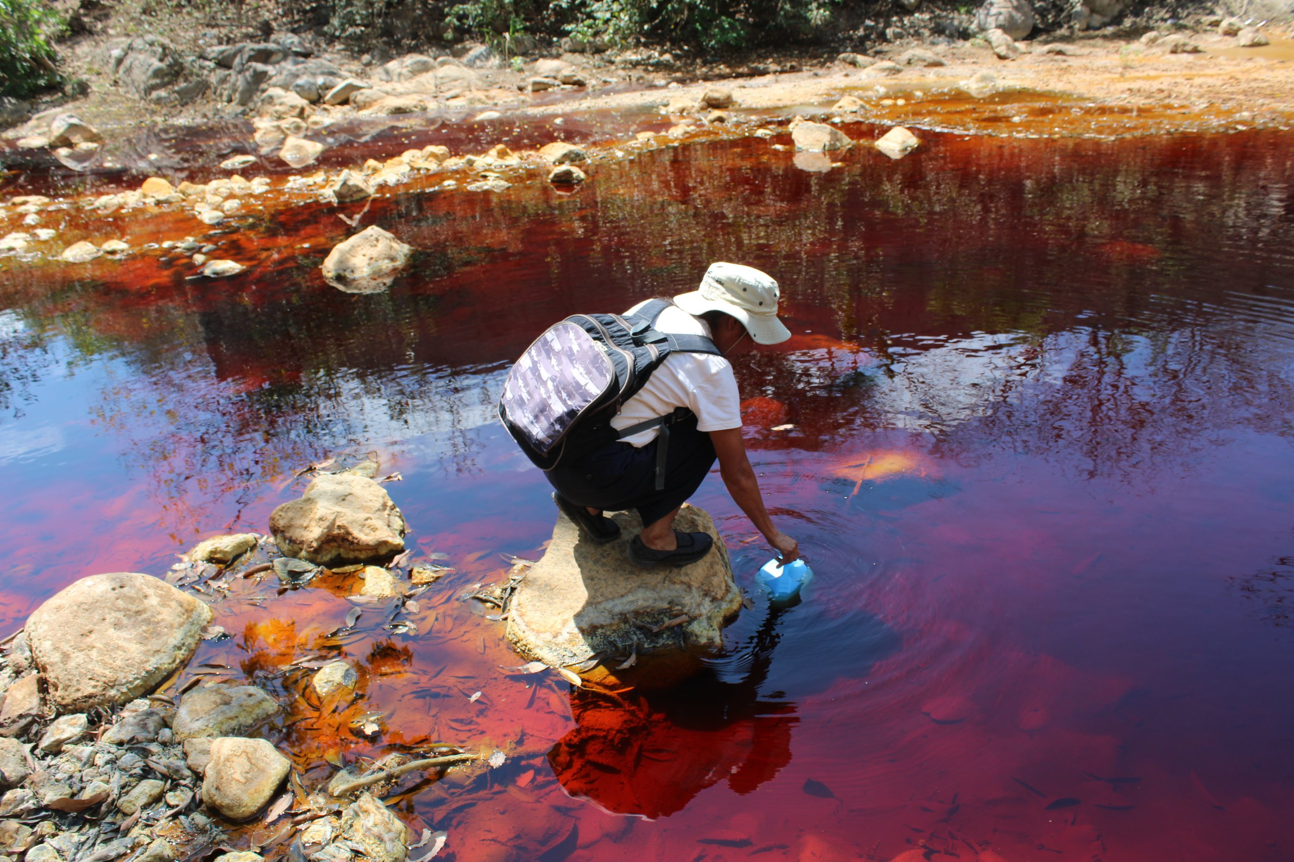 Mujer toma una muestra de un río aparentemente contaminado