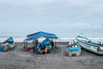 en la playa de La Chorrera, una pescadora y dos hombres revisan y ordenan la pesca sobre el bote. Foto: Irina Dambrauskas