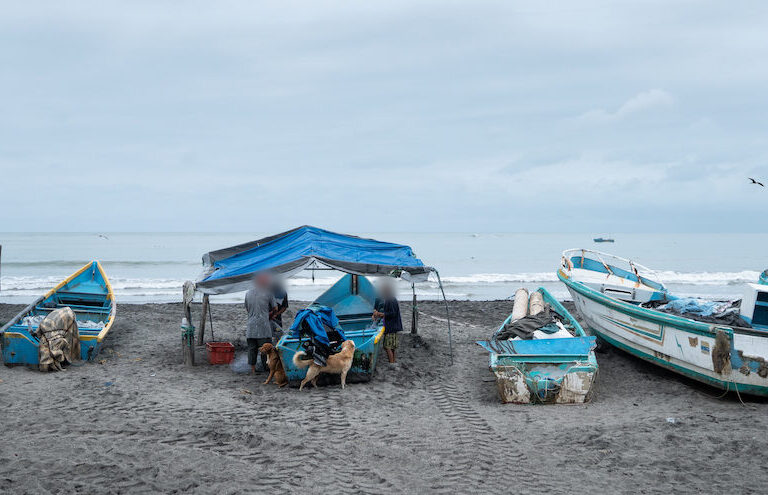 en la playa de La Chorrera, una pescadora y dos hombres revisan y ordenan la pesca sobre el bote. Foto: Irina Dambrauskas