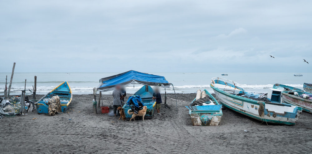 en la playa de La Chorrera, una pescadora y dos hombres revisan y ordenan la pesca sobre el bote. Foto: Irina Dambrauskas