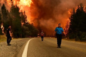 Personas caminan por una carretera mientras un incendio forestal arde en El Hoyo, Patagonia, Argentina, el jueves 8 de enero de 2026. Foto: AP / Maxi Jonas