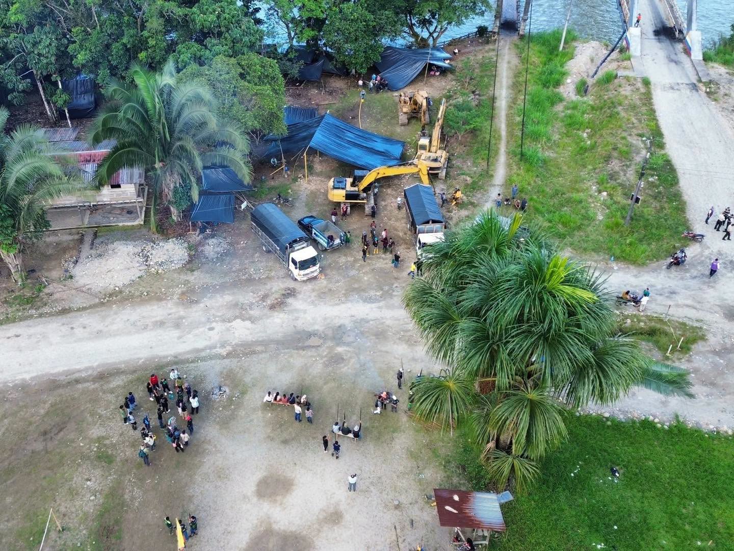 Arriba se observa la instalación del campamento de Terraturismo con plásticos negros, vehículos y maquinaria pesada. Abajo, gente de la comunidad vigila las actividades. Foto: cortesía Lanceros Digitales