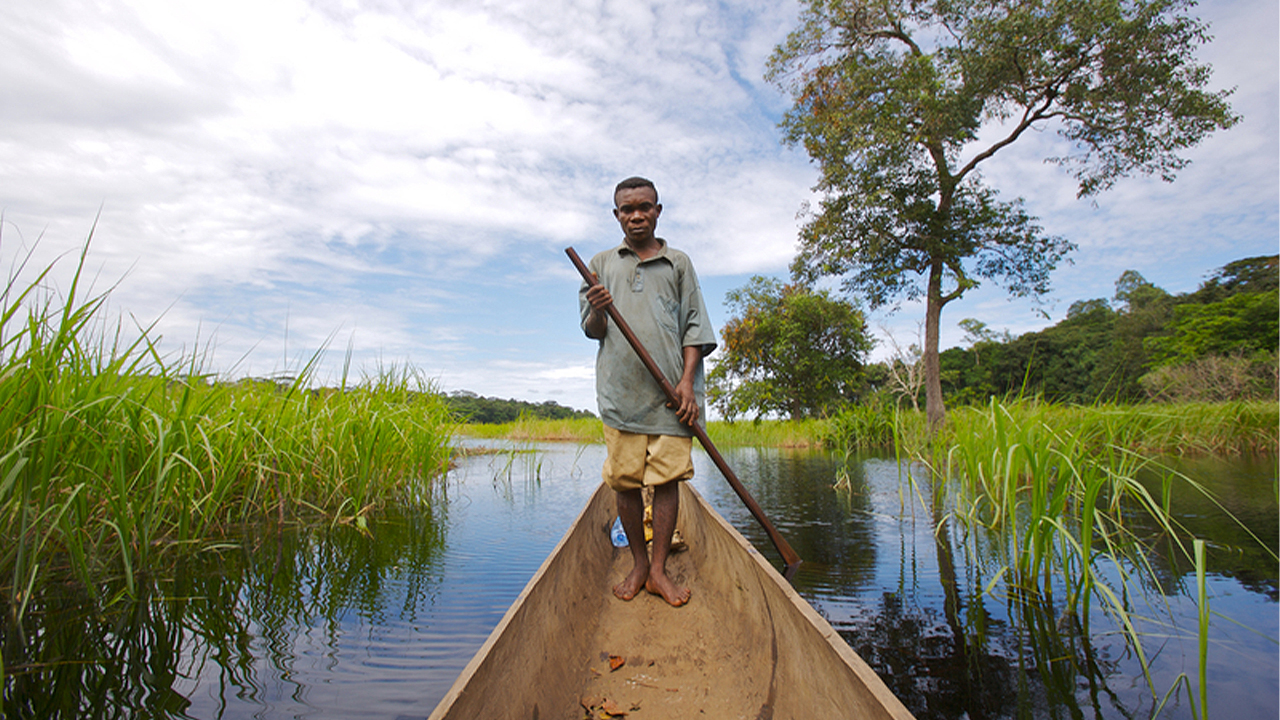 Un pêcheur local guide son bateau dans les eaux du Lac Tumba.