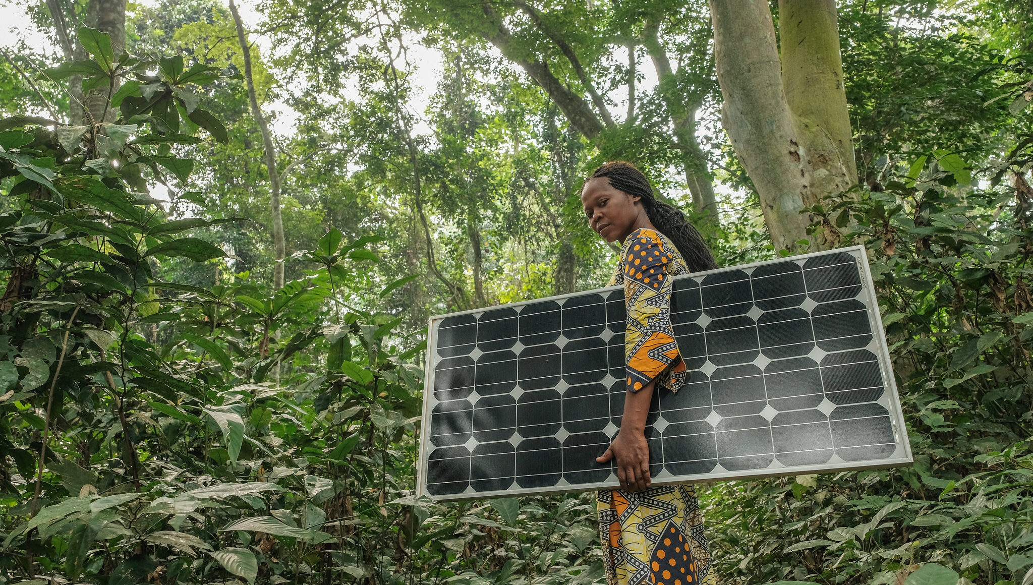 Une femme porte un paneau solaire à Yangambi, DRC. Image de Axel Fassio/CIFOR.