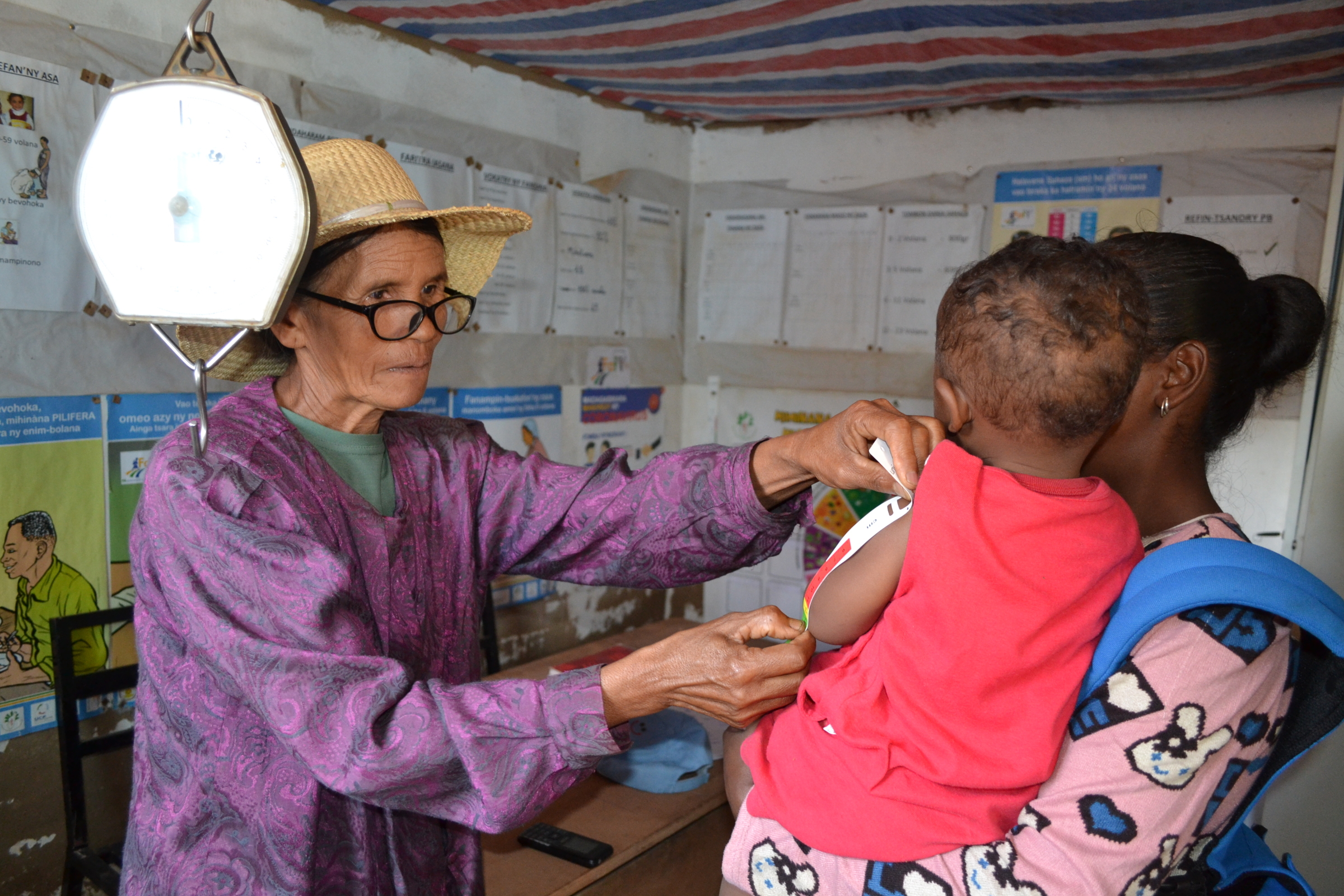 Isabelle Rakotondravelo, agent communautaire au Centre communautaire de nutrition de Mahazina, mesurant le périmètre brachial d’un enfant diagnostiqué avec une malnutrition. Photo prise par Nirina Rakotomiarintsoa, journaliste-photographe, avec son aimable autorisation.
