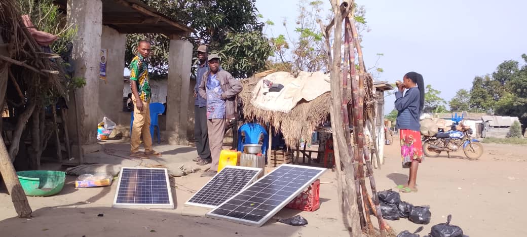 De l'énergie solaire à Lumbwe. N’étant pas connecté au réseau de Kipay Energy, un commerçant local entretient ses trois panneaux photovoltaïques pour tenir son alimentation. Image de Willy Mbuyu pour Mongabay.