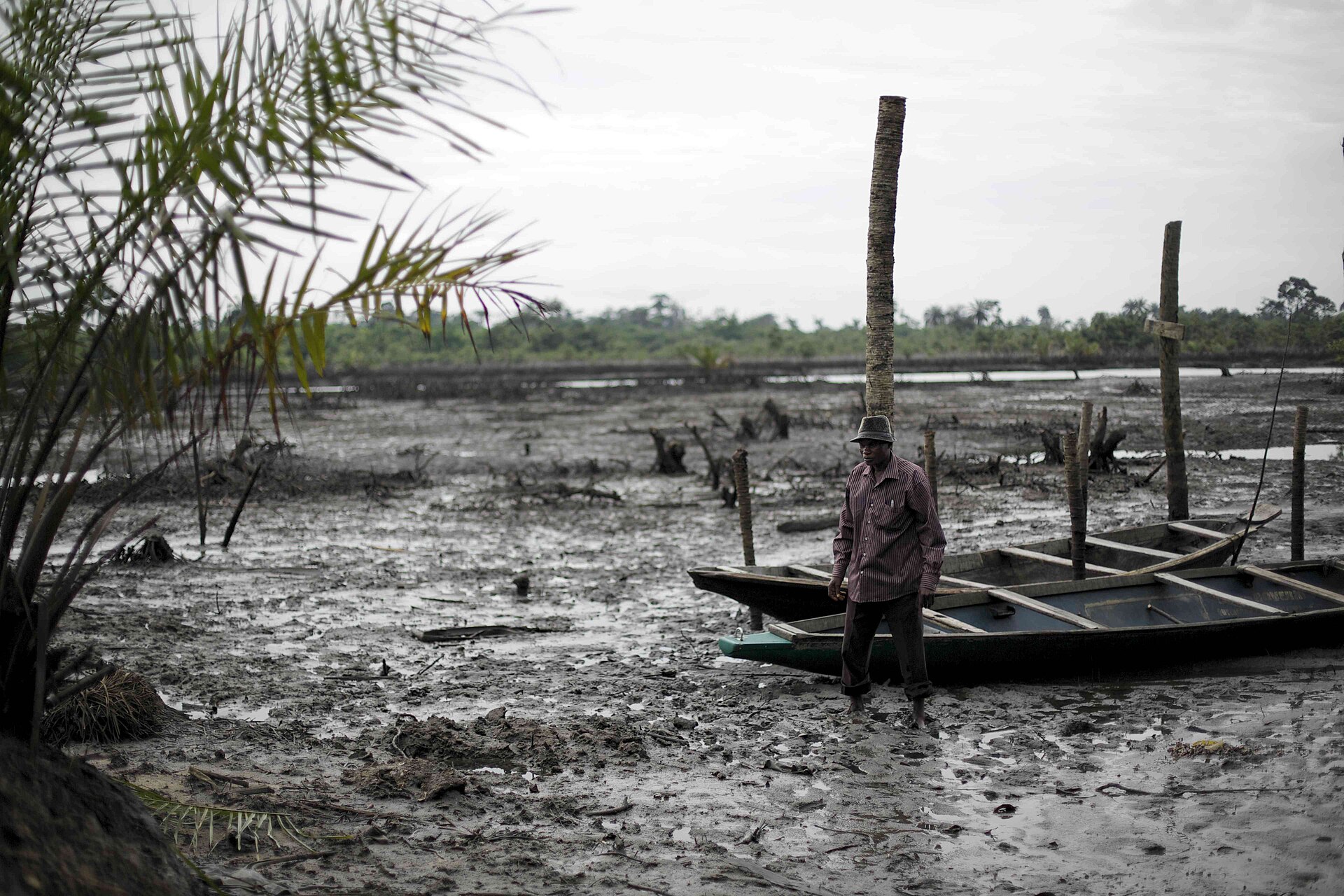 Monday Gboro se tient devant une marée noire dans la communauté de Kegbara-Dere, dans l'État de Rivers, au Nigéria. Image de Luka Tomac/Amis de la Terre International via Wikimédia Commons (CC BY-SA 2.0).