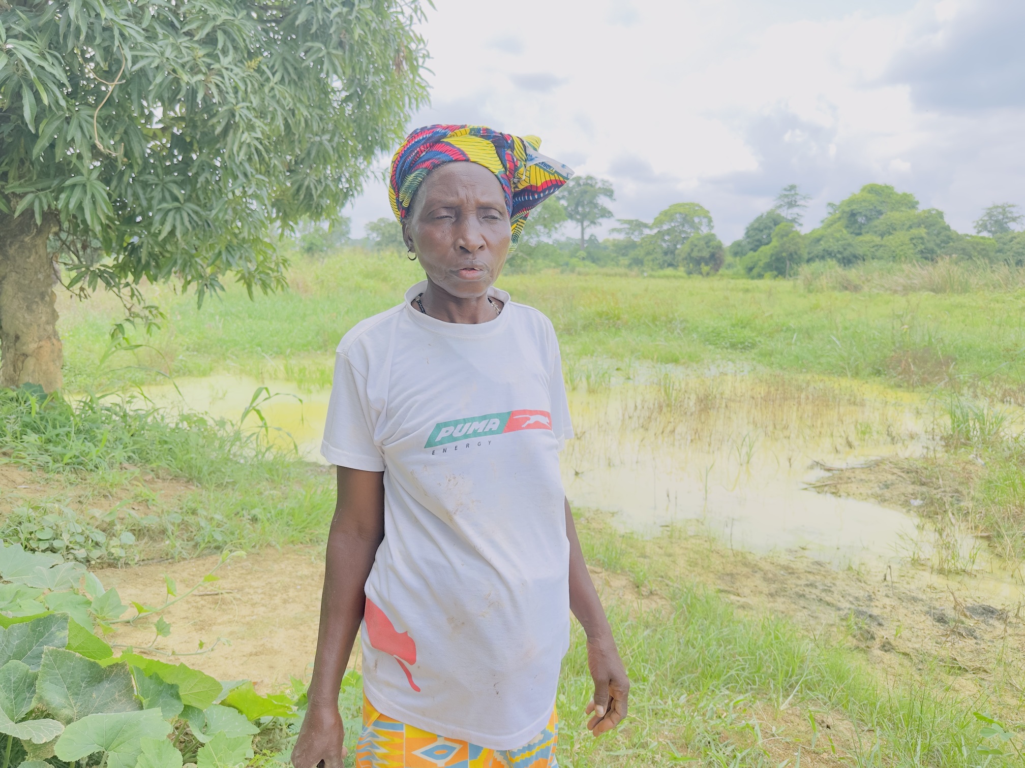 Une agricultrice pose près de la partie de sa parcelle maraîchère touchée par les écoulements de boue, dans le quartier Gagou-Sossoribougou, à Daoukro. Image de Ella Djiguimde pour Mongabay.