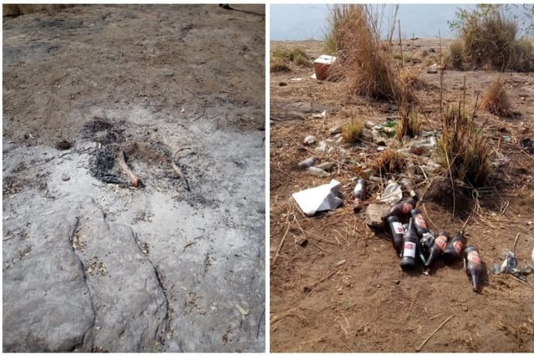 Image shows remnants of a camp fire and empty liquor bottles on a hilltop in Kodaikanal, India