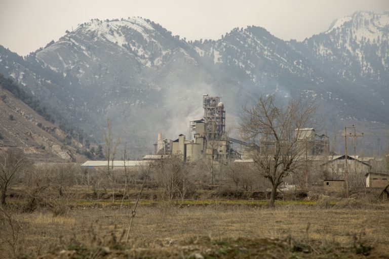 Image shows a factory with snowy mountains in the background