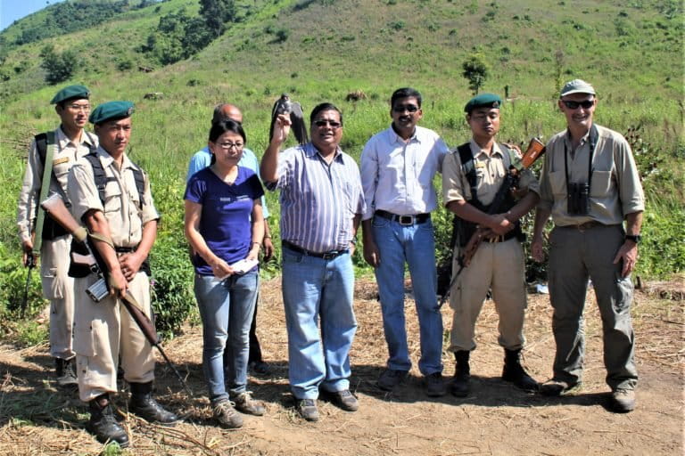 Image shows a group of people standing side by side releasing a bird