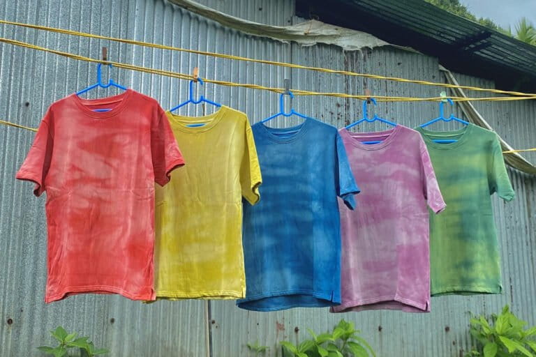 Image shows a row of colourful t-shirts