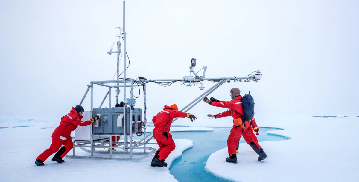 Scientists place a portable climate observatory, across an open-water lead in the Arctic in December 2020. Image by Lianna Nixon-Alfred-Wegener Institut via Wikimedia Commons (CC BY 4.0).
