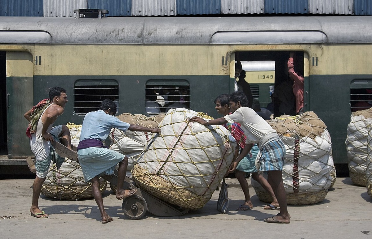 Workers pushing cotton bales at Kolkata railway station. Cotton bales are a key raw material for the textile industry. Image by Jorge Royan via Wikimedia Commons (CC BY-SA 3.0)"