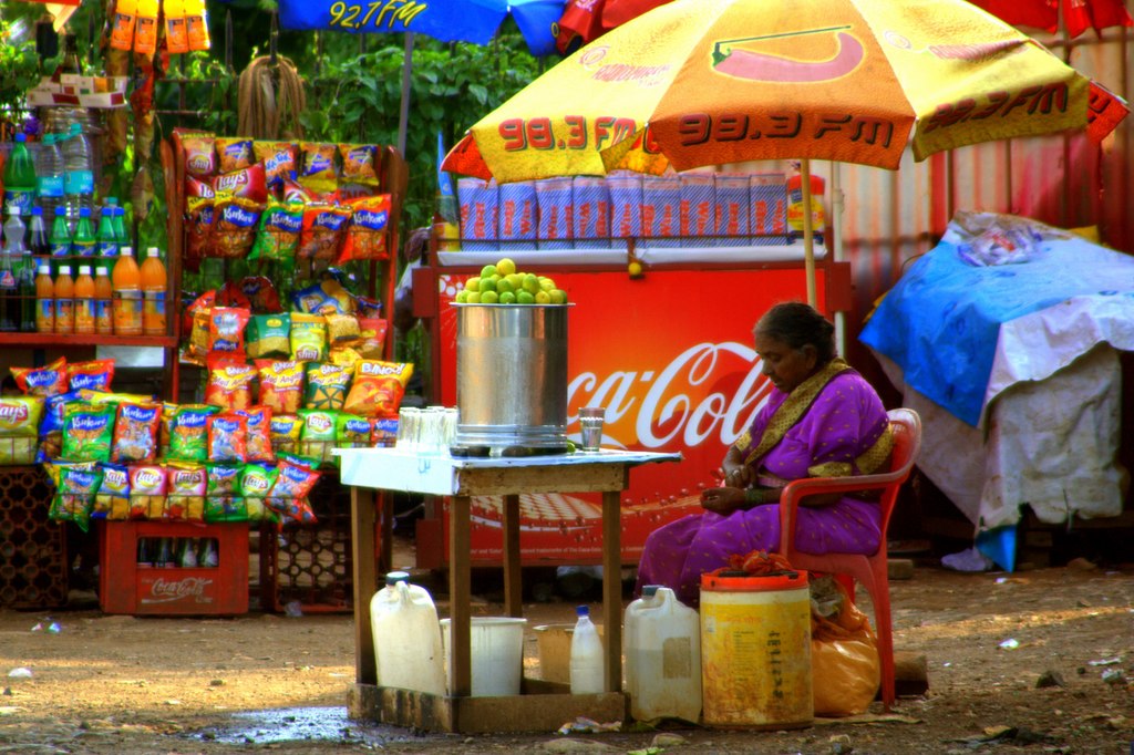 A woman sells lemonade while taking shade under an umbrella. A critical but under-studied dimension of public health is the effect of climate change impacts — especially heat — on women’s health. Representative image by utpal via Wikimedia Commons (CC BY 2.0).