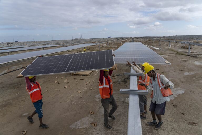 Workers install solar panels in Karim Shahi village, Bhuj district, Gujarat in 2023. India received around $2.4 billion in 2024 for project type interventions in clean energy generation, with solar PVs leading the surge. (AP Photo/Rafiq Maqbool)