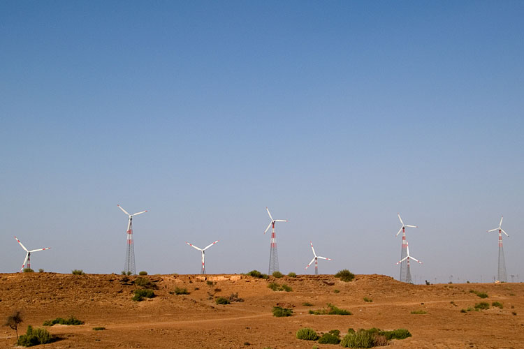 Wind turbines in Jaisalmer. The approach of 'green ensconcement’ seeks to implement energy transition mindfully, prioritising the utility value attached by diverse peoples to landscapes. For example, a pastoralist in Jaisalmer would prefer the vegetation and waterbodies in the desert left untouched by industries. Image by Nagarjun Kandukuru via Wikimedia Commons (CC BY 2.0).