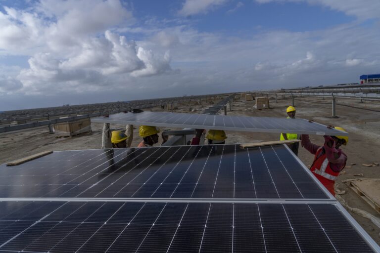 Workers install solar panels in Gujarat. (AP Photo/Rafiq Maqbool)
