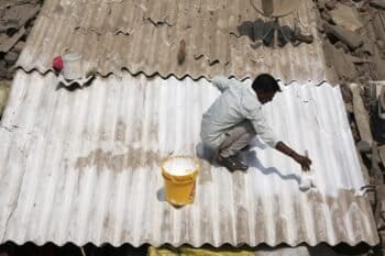 A man applies reflective paint to the roof of a house to cool the indoors in Ahmedabad. (AP Photo/Ajit Solanki)