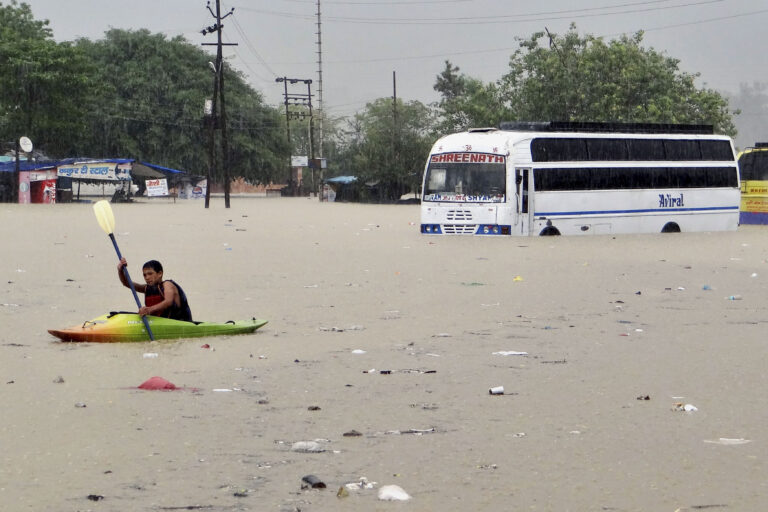 A man rows past a bus partly submerged in flood water in Rishikesh in June 2013. Extreme rain during the monsoon led to flash floods, cloudbursts and landslides during this time in the Western Himalayas. (AP Photo)